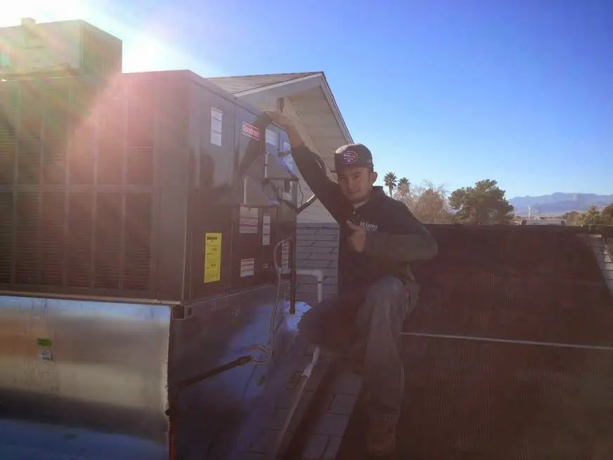 HVAC technician performing Air Duct Repair on a rooftop unit in Salina